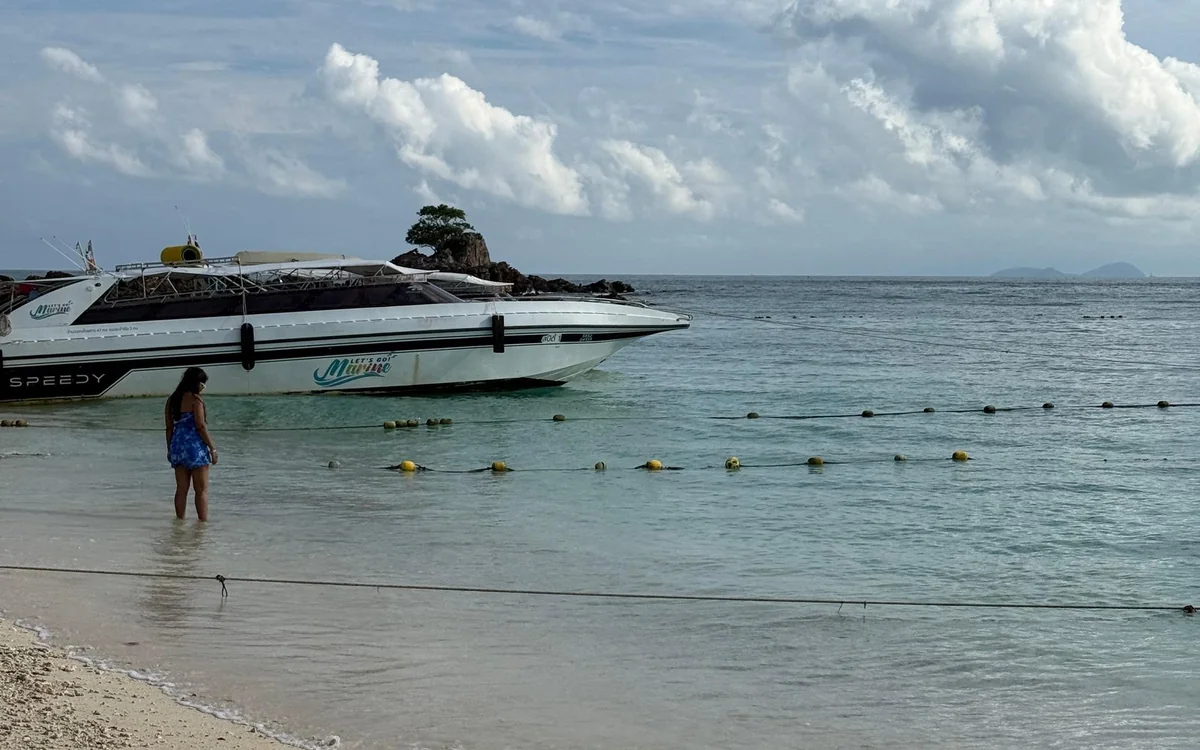A family speedboat anchored off a white sand beach at the Phi Phi Islands